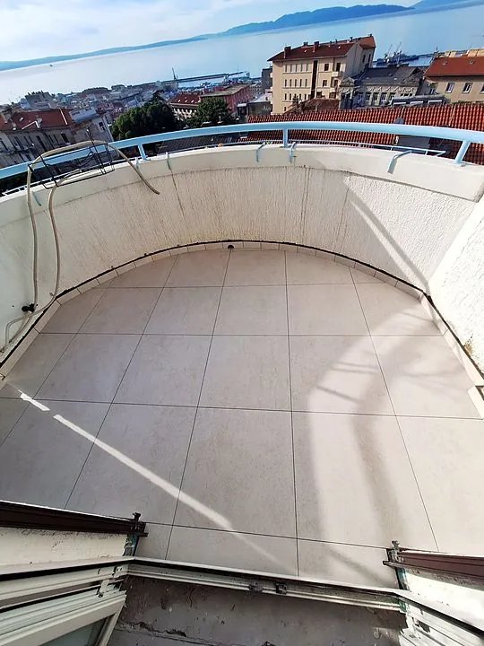 Balkon s pogledom na Rijeku. Zaobljeni rub izrezan prema obliku ograde.