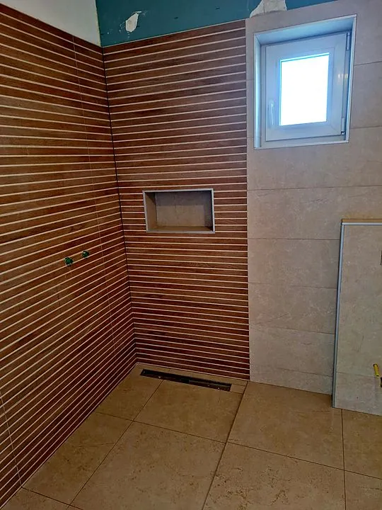 Tuš s nišom. Zid s reljefnim letvicama i tuš kanalica.